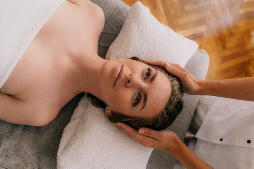 A Woman Lying on Bed Having an Acupuncture on Her Face in Burnaby facial rejuvenation acupuncture clinic